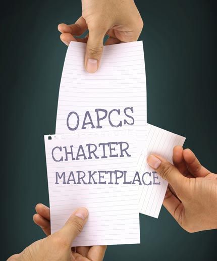 hands holding 3 pieces of paper together spelling out OAPCS Charter Marketplace