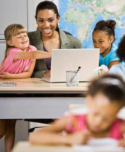 African Amerian teacher with two 3rd grade children on a laptop computer